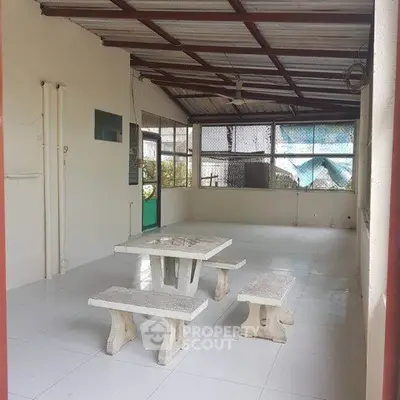 Spacious covered patio with stone table and benches, ideal for outdoor gatherings.