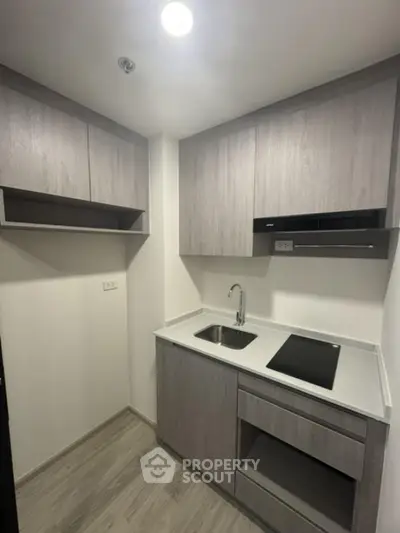 Modern compact kitchen with sleek cabinetry and electric cooktop