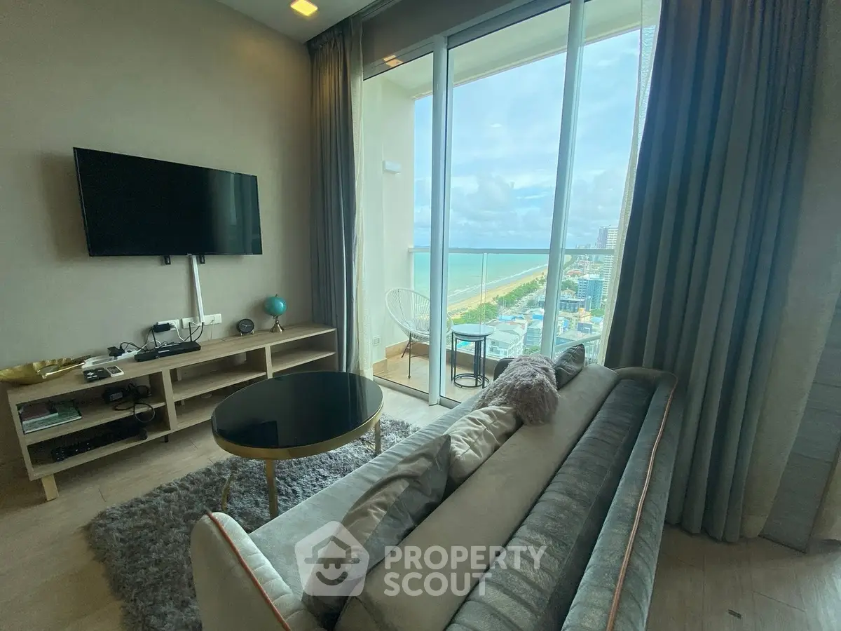 Luxurious living room with stunning ocean view from high-rise balcony, modern decor and cozy seating.