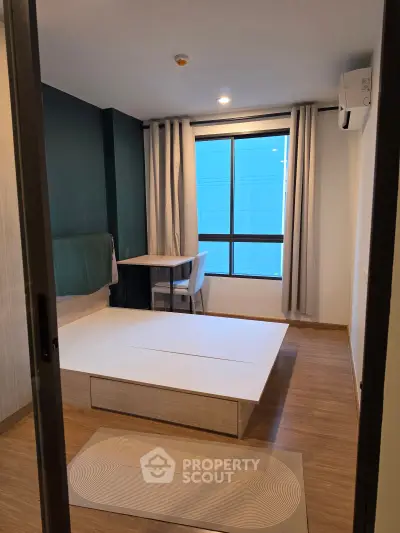 Modern bedroom with minimalist design and large window for natural light.