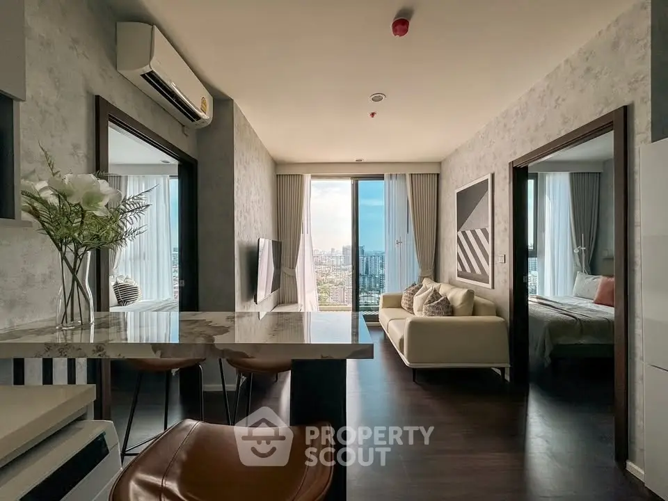 Modern apartment interior with open layout, stylish decor, and city view from large windows.