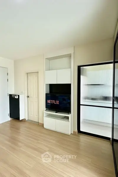 Modern living room with sleek TV setup and wooden flooring