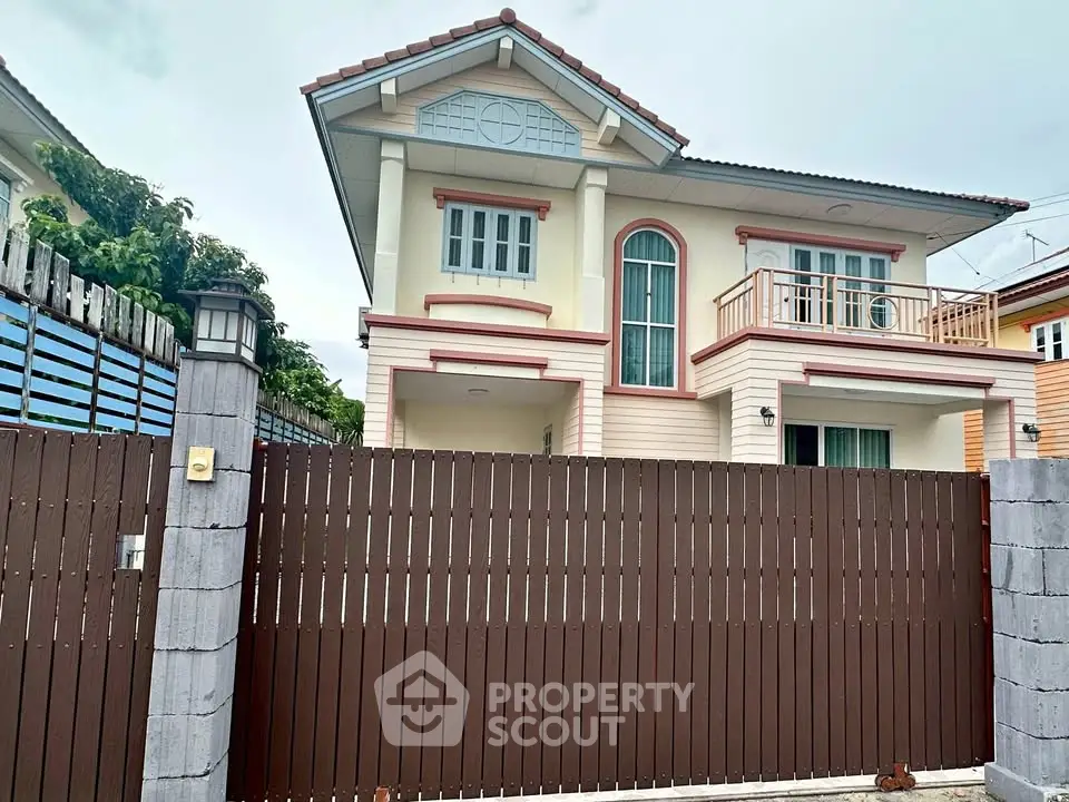 Charming two-story house with balcony and modern fence in a serene neighborhood.