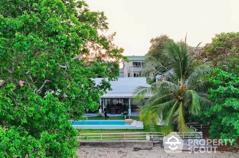 Stunning beachfront property with lush greenery and private pool, perfect for luxury living.