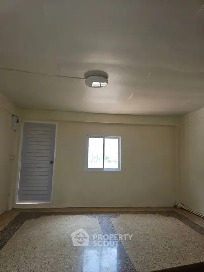 Spacious empty room with window and tiled floor, ideal for customization.