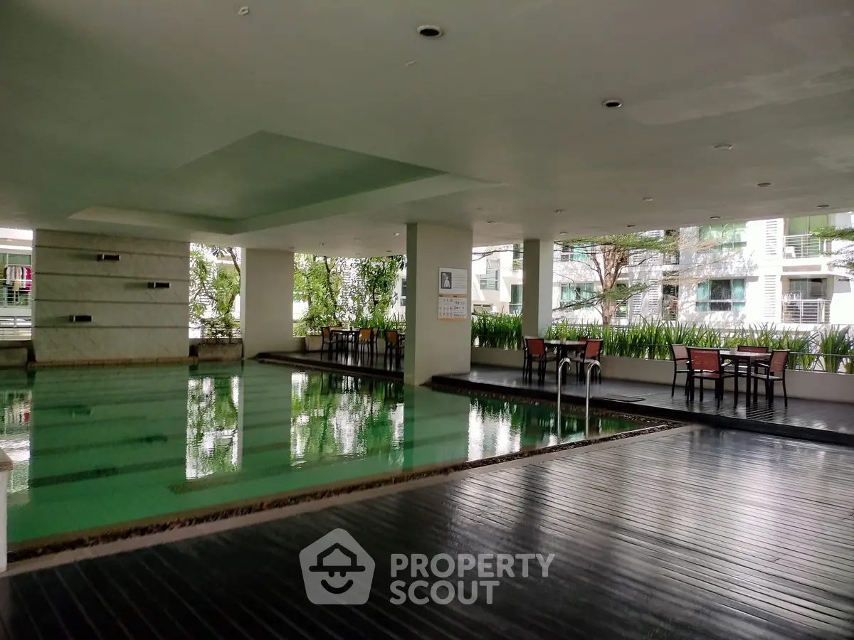 Luxurious indoor pool area with stylish seating and greenery, perfect for relaxation and leisure.