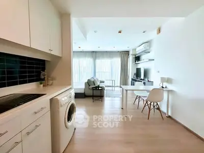 Modern open-plan living room with kitchen and washing machine, bright and airy design.