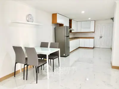 Modern kitchen with dining area, sleek appliances, and elegant tile flooring.