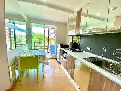 Modern kitchen with open layout and balcony view, featuring sleek appliances and dining area.