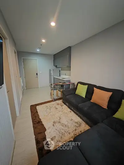 Modern living room with cozy sofa and open kitchen layout in stylish apartment.