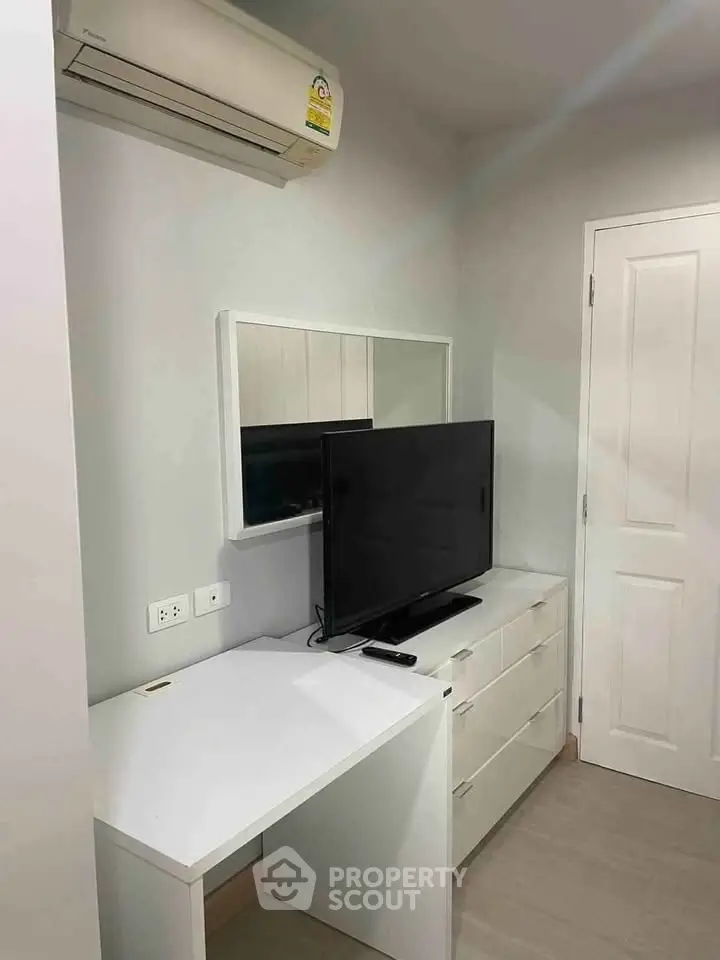 Modern bedroom with sleek white furniture and wall-mounted air conditioner