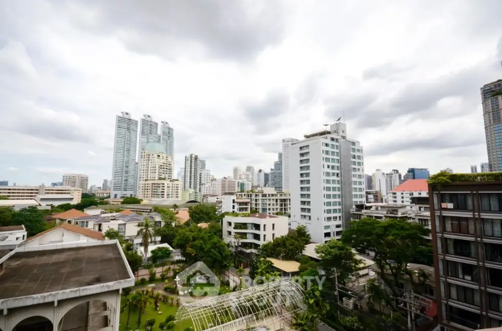 Stunning cityscape view from high-rise apartment balcony with lush greenery and modern skyscrapers.