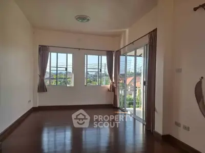 Spacious empty living room with large windows and balcony access, offering abundant natural light and scenic views.