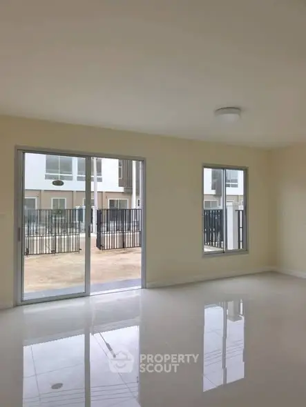 Spacious empty room with large windows and sliding glass door, perfect for natural light.