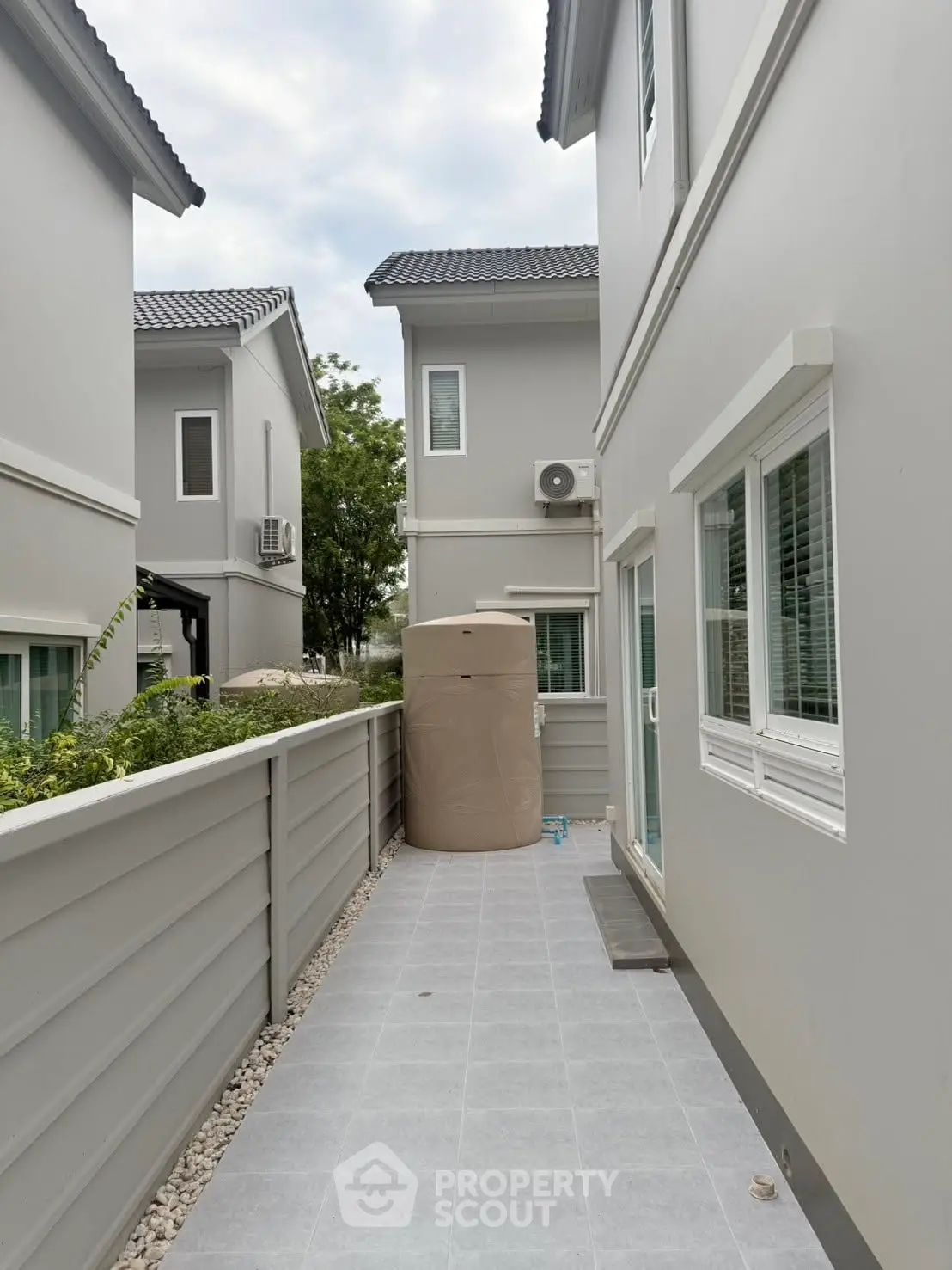 Modern townhouse exterior with clean lines and neutral colors, featuring a narrow side pathway.