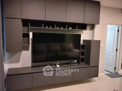 Modern living room with sleek entertainment center and large flat-screen TV.