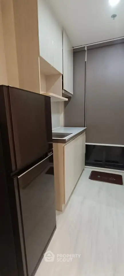 Modern kitchen with sleek cabinets and compact fridge in stylish apartment.