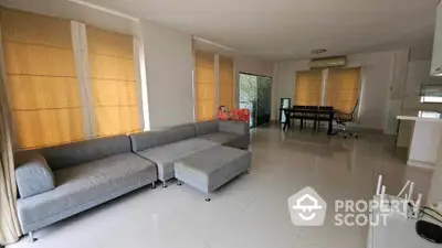 Spacious living room with modern gray sectional sofa and large windows, offering ample natural light and open space.