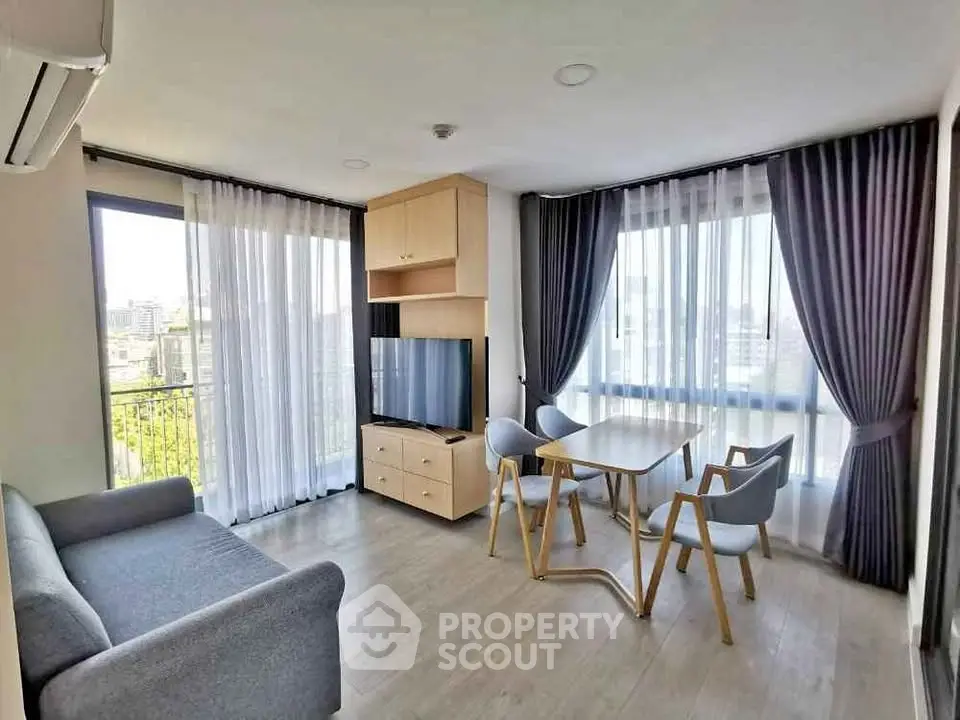 Modern living room with large windows, stylish furniture, and city view.