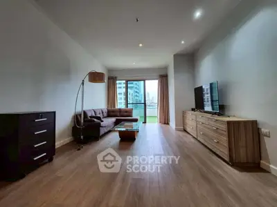 Spacious modern living room with wooden flooring and large window view.
