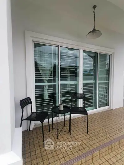Charming balcony with modern furniture and sliding glass doors, perfect for relaxation.