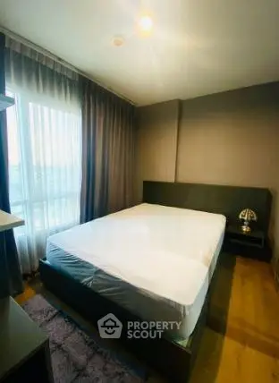 Spacious bedroom with large window and modern decor in a stylish apartment.