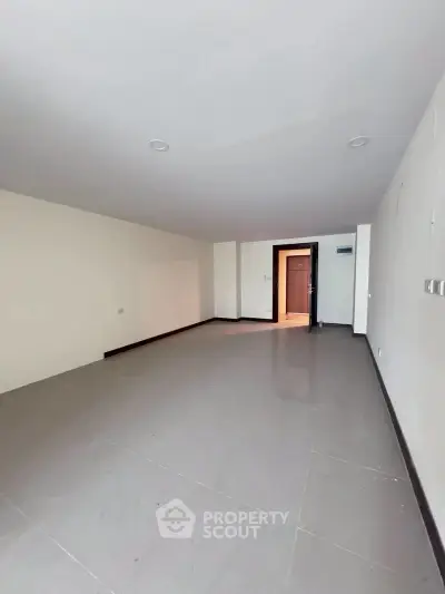 Spacious empty room with tiled flooring and recessed lighting, ideal for customization.