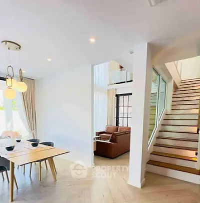 Modern open-plan living and dining area with stylish staircase and elegant lighting.