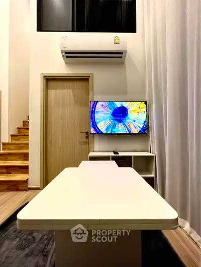 Modern living room with stylish staircase and wall-mounted TV, featuring sleek air conditioning unit.