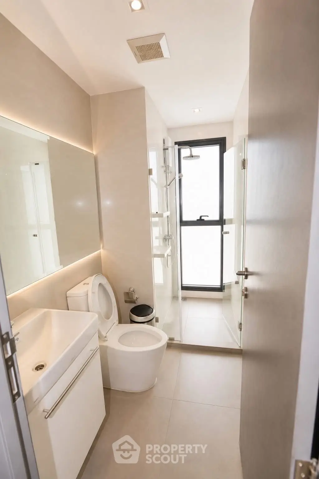 Modern bathroom with sleek fixtures and glass shower enclosure in a contemporary apartment.