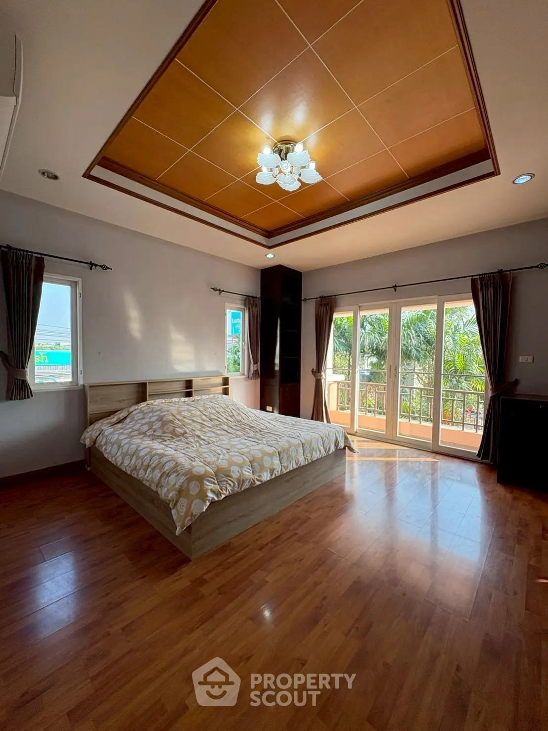 Spacious bedroom with wooden flooring and balcony access, featuring large windows for natural light.