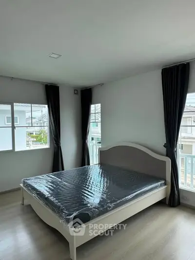 Spacious bedroom with large windows and modern bed in a bright, airy setting.