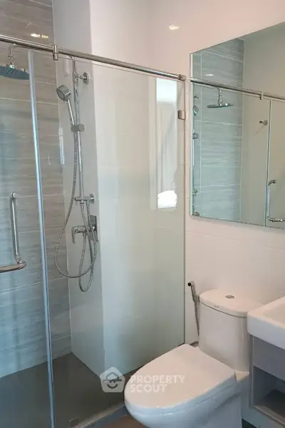 Modern bathroom with glass shower and sleek fixtures in a contemporary apartment.