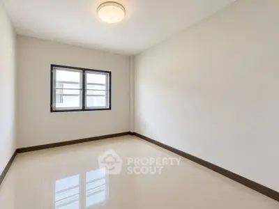 Spacious empty room with glossy tiled floor and large window, perfect for customization.