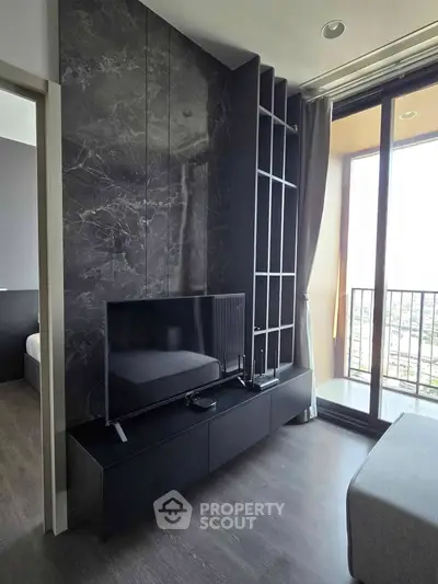 Modern living room with sleek black entertainment unit and large window balcony view.