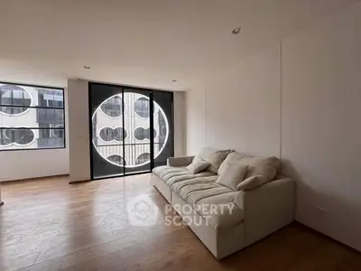 Modern living room with unique circular window design and cozy sofa