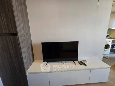 Modern living room with sleek TV setup and adjacent laundry area