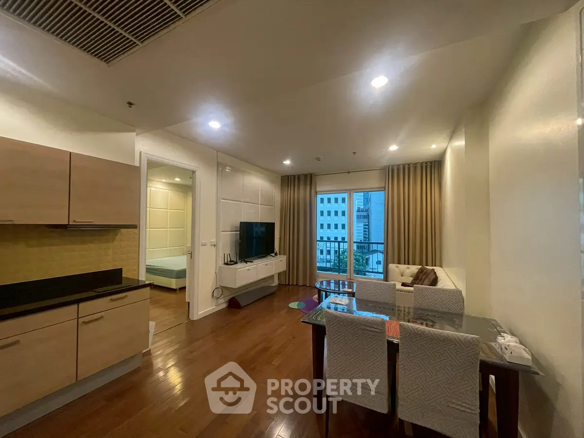 Spacious modern living room with open kitchen and city view, featuring elegant dining area and cozy seating.