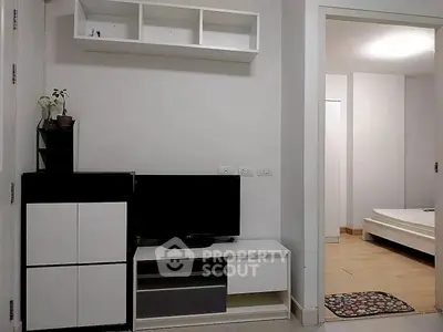 Modern living room with sleek TV stand and open view into minimalist bedroom.
