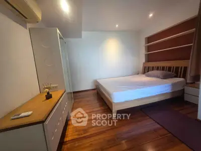 Spacious bedroom with wooden flooring and modern furniture in a stylish apartment.