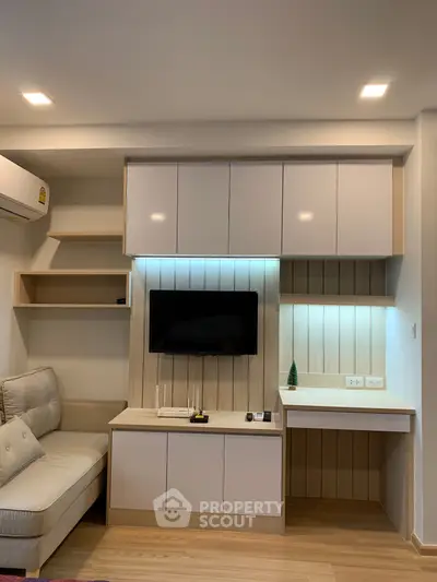 Modern living room with built-in TV unit and cozy seating area, perfect for relaxation and entertainment.