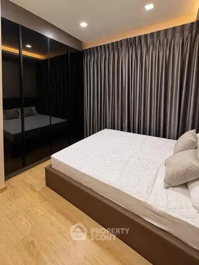 Modern bedroom with sleek design, featuring a large bed and mirrored wardrobe, perfect for urban living.