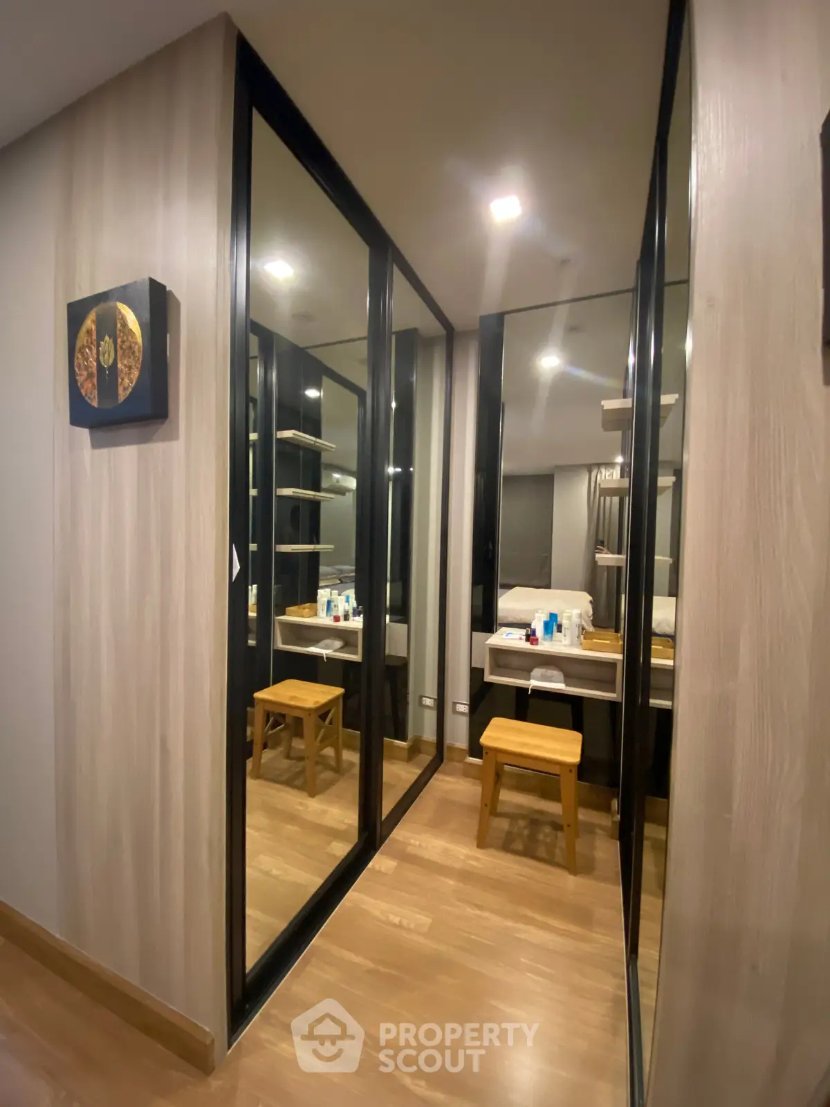 Modern walk-in closet with mirrored sliding doors and wooden flooring