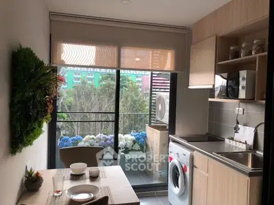 Modern kitchen with balcony view, featuring washing machine and sleek cabinetry.