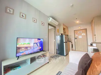 Modern living room with TV, air conditioning, and kitchen area in open layout apartment.