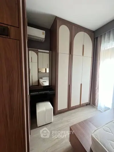 Modern bedroom with stylish wardrobe and vanity area, featuring natural light and elegant design.