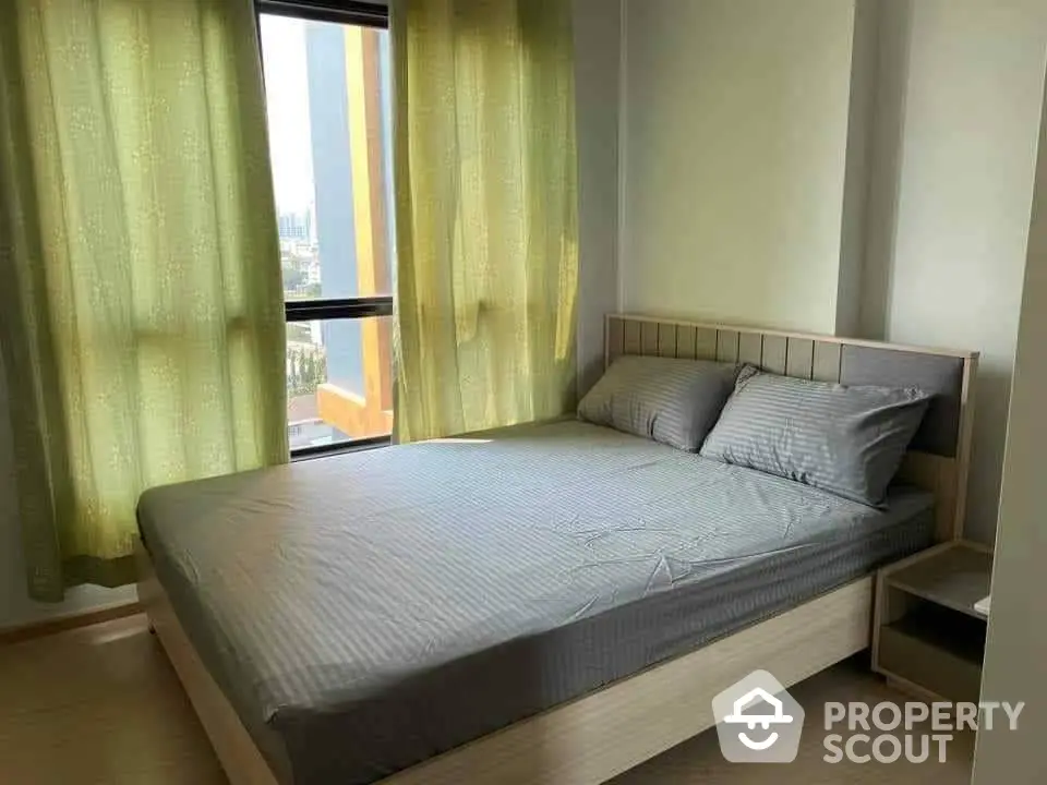 Cozy bedroom with ample natural light, modern furnishings, and a serene city view, perfect for restful living in an urban setting.