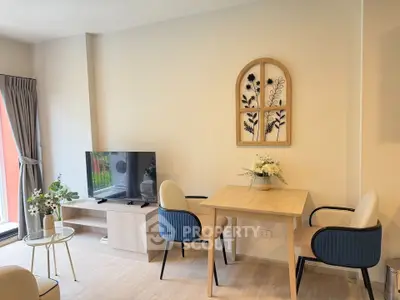 Modern living room with stylish decor and natural light, featuring a cozy seating area and wall art.