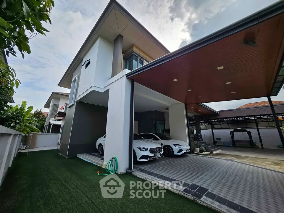 Modern two-story house with carport and luxury cars parked, featuring sleek architectural design.