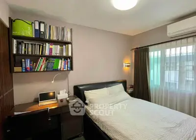 Cozy bedroom with study area, featuring a comfortable bed, desk, and bookshelf, ideal for work and relaxation.
